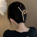 Acetate hair claw clip with pearl and rhinestone details.